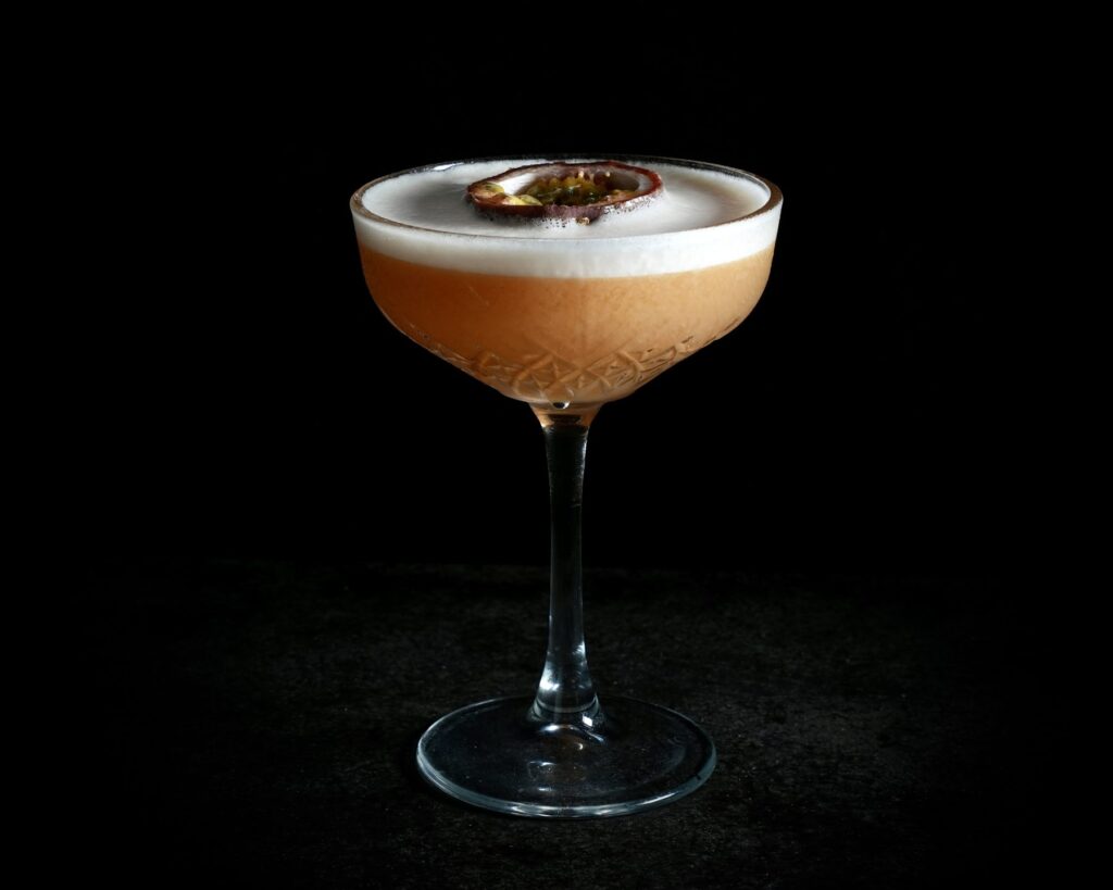 Sour cocktail met passievrucht in een coupeglas