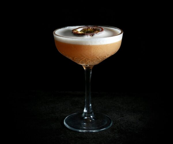 Sour cocktail met passievrucht in een coupeglas