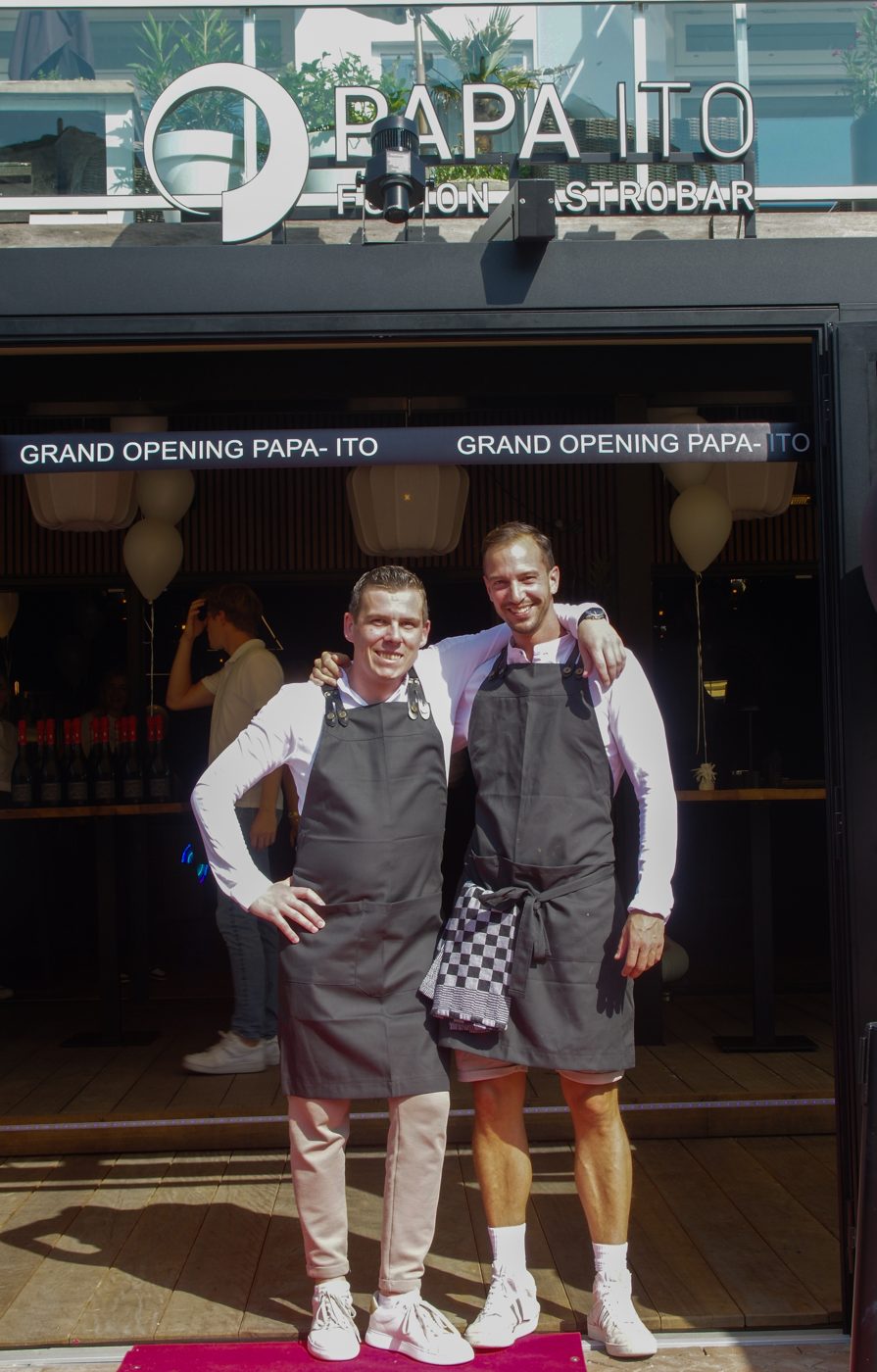 Floris en Kevin onder de Grand Opening banner van Papa Ito